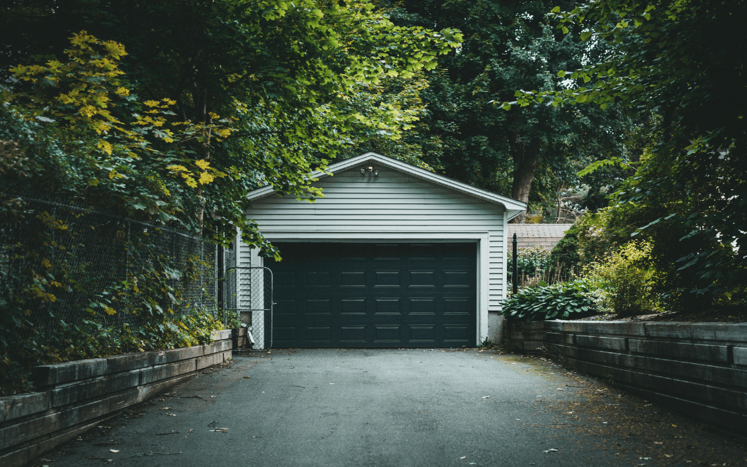 Black garage door with tress surrounding